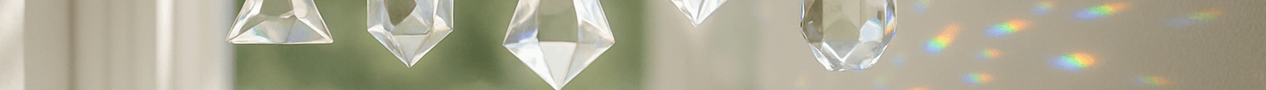 Mini crystal prism suncatchers casting rainbows beside a window