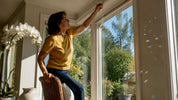 Woman hanging crystal suncatcher by window
