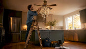 Installer attaching crystals to ceiling fan chandelier