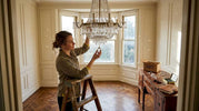 Person inspecting crystal chandelier in elegant dining room