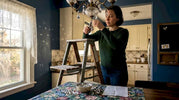 Homeowner repairing chandelier crystals in dining room