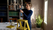 Woman arranging crystal prisms on chandelier