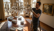 Installer attaches chandelier crystals in formal dining room