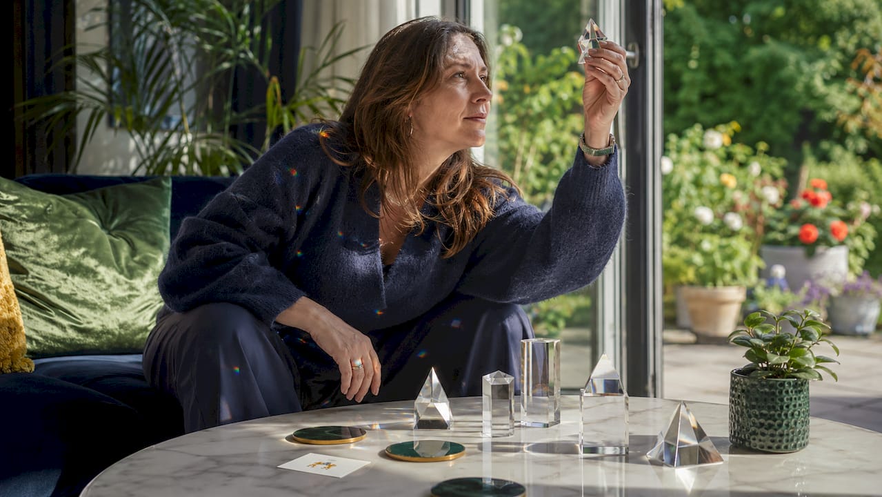 Woman arranging crystal prisms on wooden table