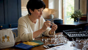 Woman examining Swarovski crystal prisms at home desk