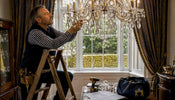 Electrician adjusting crystal chandelier on ladder