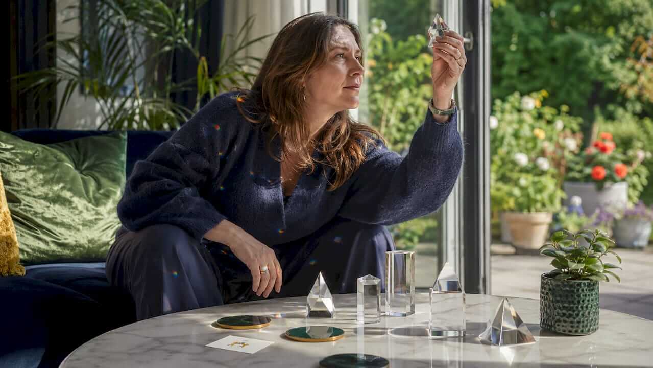 Woman arranging crystal prisms on wooden table