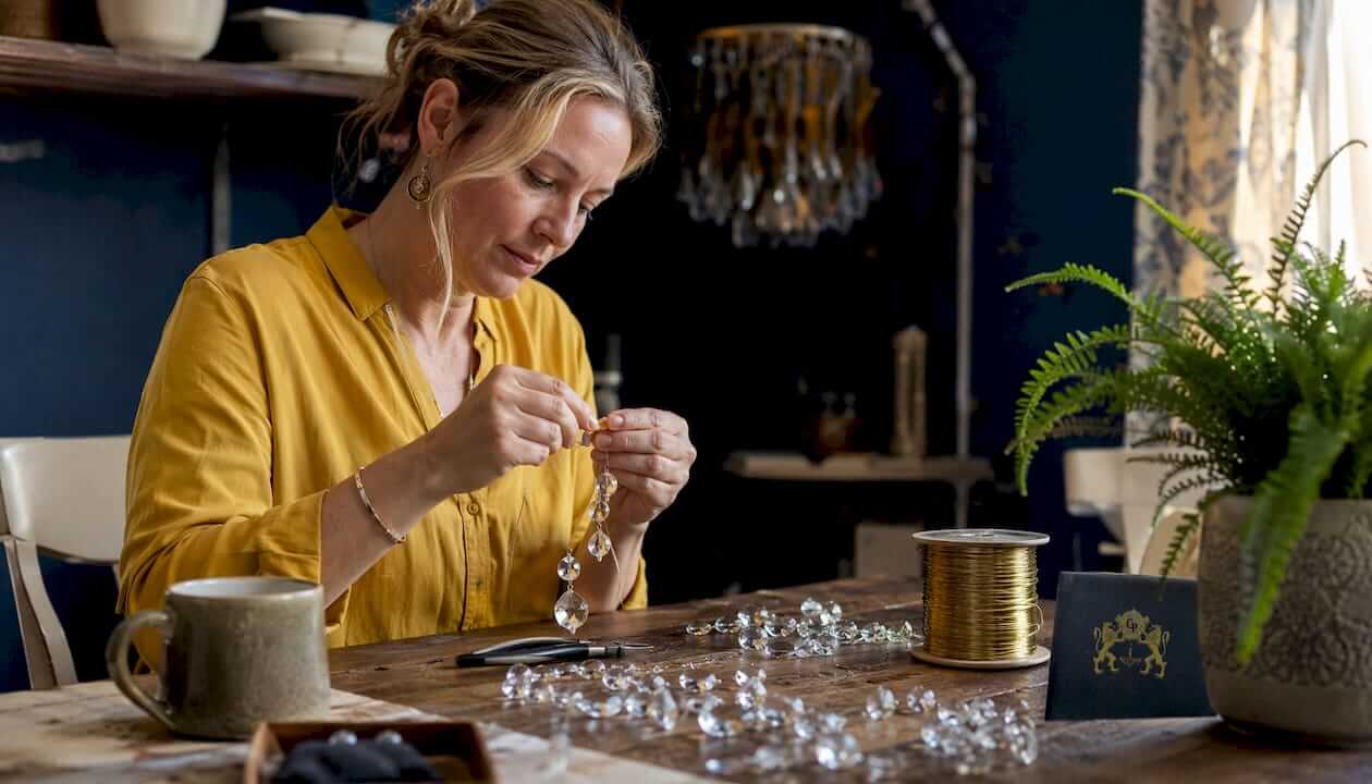 Artisan threading crystals onto brass wire