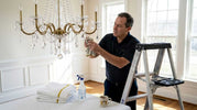 Man cleaning crystal chandelier with cloth