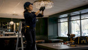 Electrician installing crystal fixture on drop ceiling