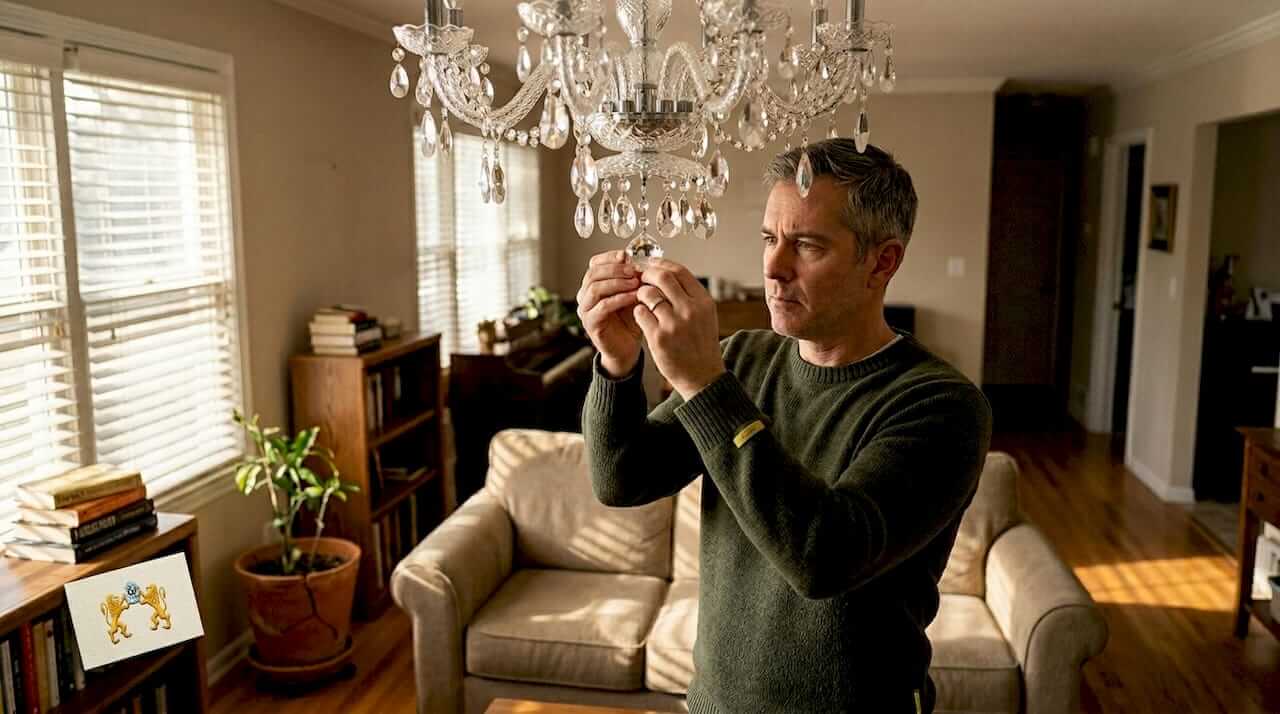 Man inspecting chandelier crystals in lived-in home