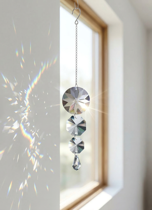 Crystal hanging ornament in front of a window with rainbow