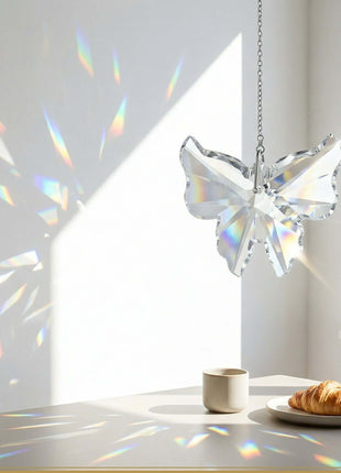 Crystal butterfly decoration casting rainbow patterns on a white surface with a cup and croissant.
