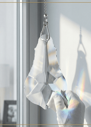 Crystal 6-inch prism hanging in front of a window with rainbow colors