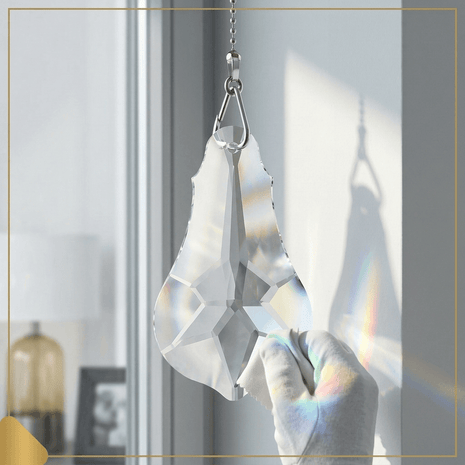 Crystal 6-inch prism hanging in front of a window with rainbow colors