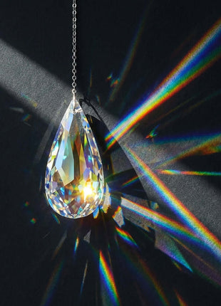 Crystal teardrop prism hanging against a dark background 