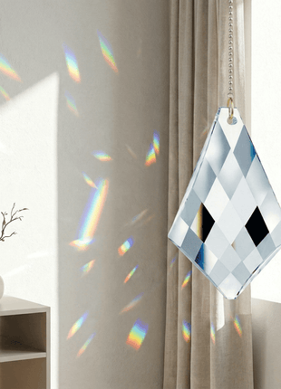 Decorative glass panel with geometric pattern hanging in a room with a vase and plant on a table.