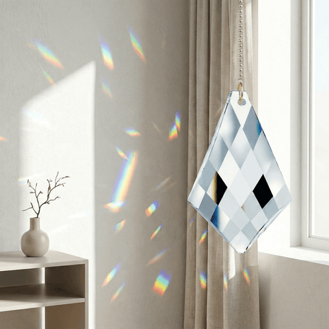 Decorative glass panel with geometric pattern hanging in a room with a vase and plant on a table.