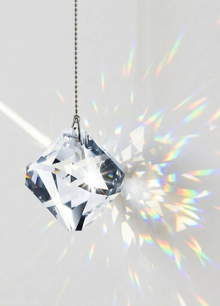 Swarovski Crystal prisms hanging from a string with rainbow on a white background