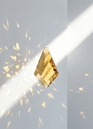 Gold diamond-shaped object with sparkling effect on a light gray background