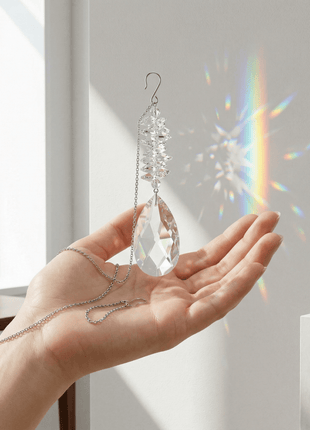 Hand holding a crystal hanging ornament with rainbow