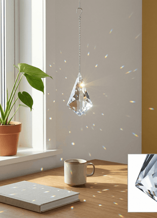 Crystal hanging ornament on a table with a plant and mug in the background