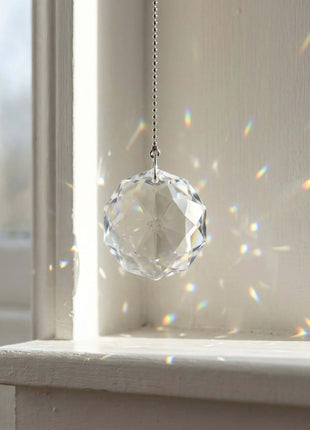 Swarovski Crystal hanging ornament on a windowsill with sunlight filtering through