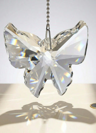 Crystal butterfly ornament on a chain against a neutral background