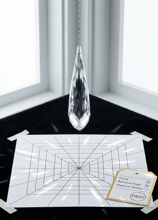 Crystal pendant hanging above a grid with a label in a room with large windows.
