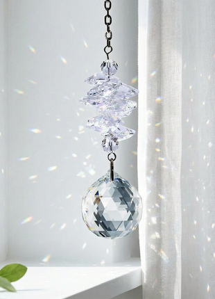 Swarovski Crystal hanging ornament in front of a window with white curtains