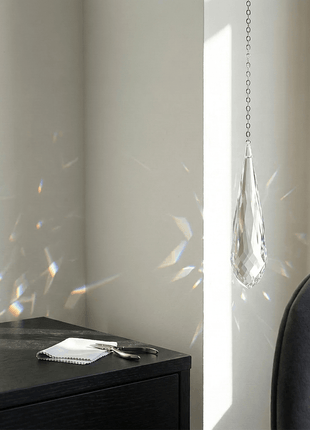 Modern interior with a black cabinet, decorative item, and hanging crystal.
