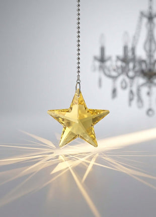 Swarovski star-shaped crystal hanging with a blurred chandelier in the background