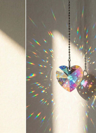 Swarovski Heart-shaped crystal prism hanging on a chain, creating rainbow patterns on a wall.