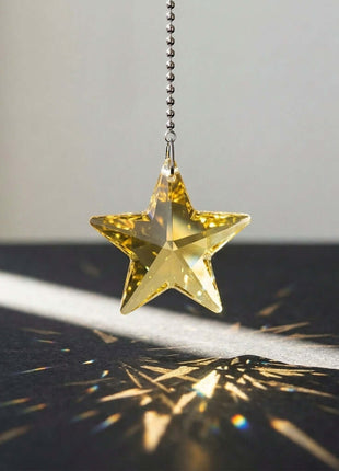Gold star-shaped pendant casting a shadow on a dark surface with a light gray background
