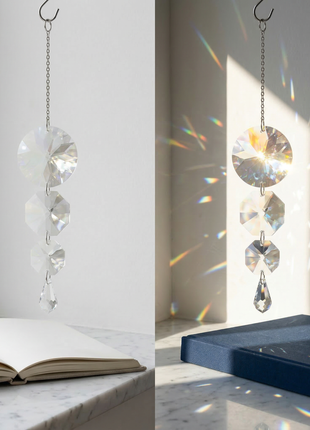 Crystal hanging ornament casting rainbow patterns on a book and white surface.