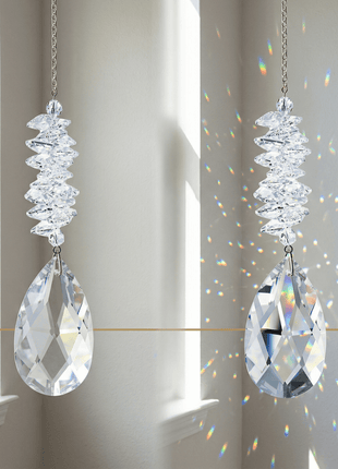 Two crystal suncatchers hanging in front of a window with rainbow