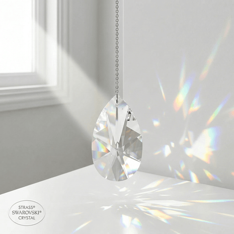 Swarovski Crystal pendant hanging on a white surface with a blurred window in the background