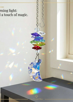 Colorful  Swarovski crystal hanging decoration on a table with rainbow light effects, in a room with a window.