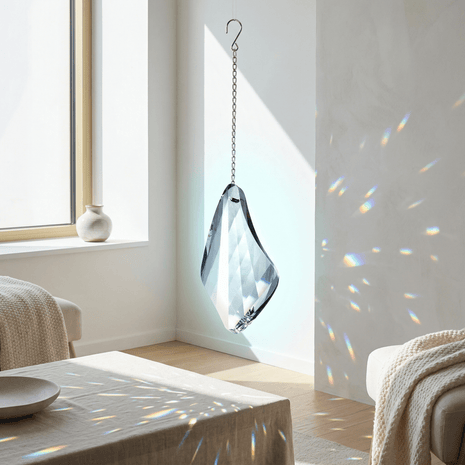 Swarovski Crystal hanging ornament with rainbow in a room with a window and furniture.