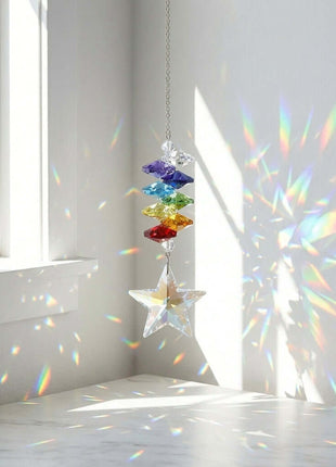 Colorful Swarovski crystal hanging ornament casting rainbow patterns on a white wall.