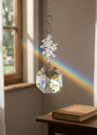 Swarovski Crystal hanging ornament creating a rainbow in a room with a window and table.