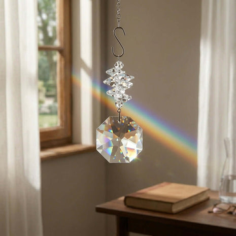 Swarovski Crystal hanging ornament creating a rainbow in a room with a window and table.
