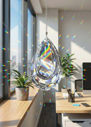 Crystal teardrop prism hanging in a bright room with office furniture and large windows.
