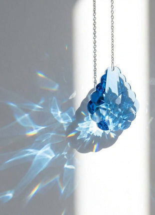 Blue crystal pendant on a chain against a gray background