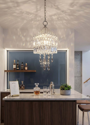 Modern kitchen island with a chandelier, bottles, and glasses by crystalplace.com