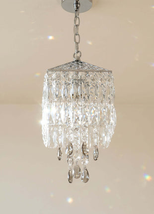 Crystal chandelier hanging against a beige wall by crystalplace.com