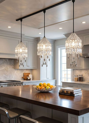 Modern kitchen with a wooden island, crystal pendant lights, and a bowl of fruit by crystalplace.com